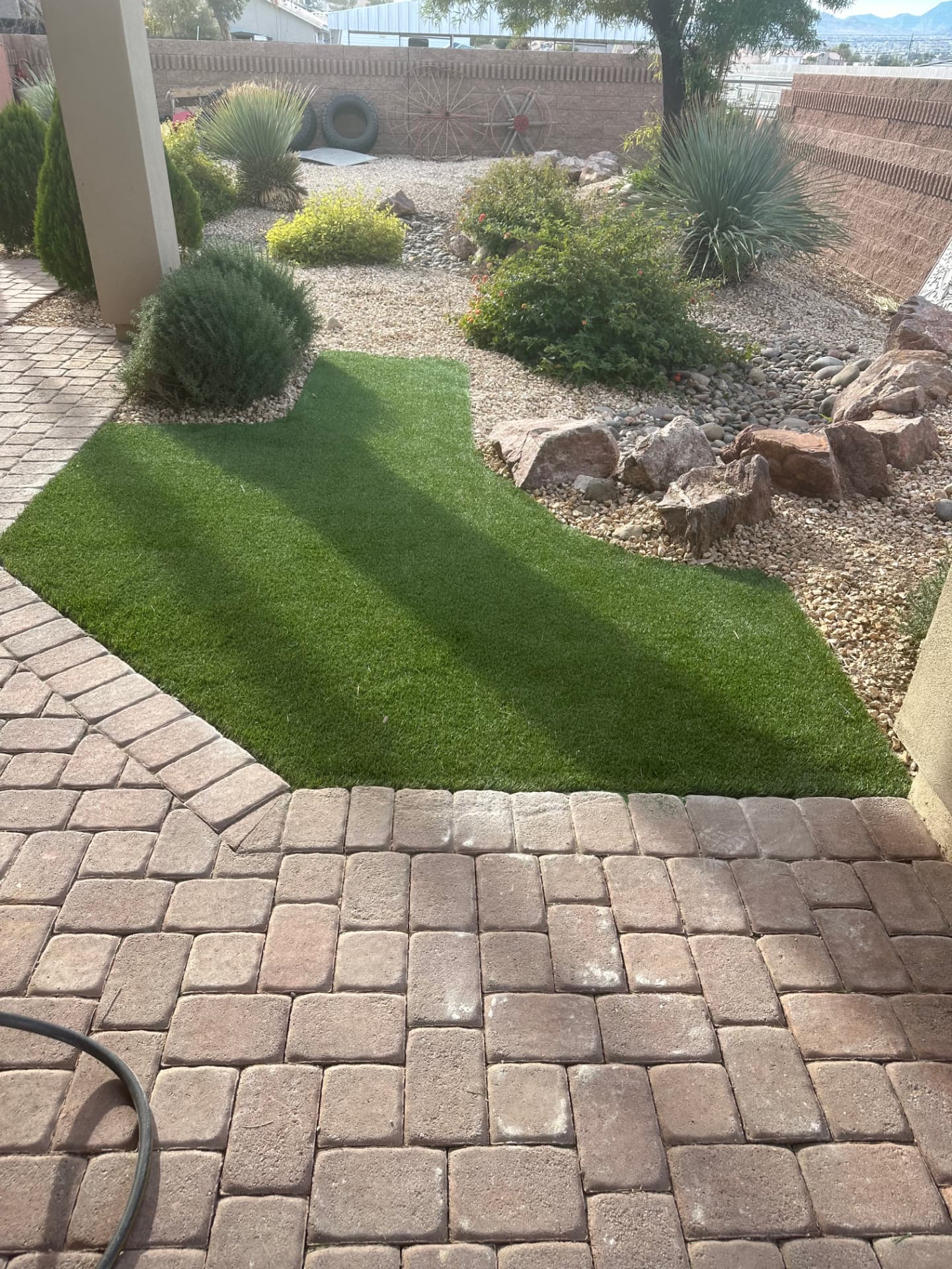 Paver patio with artificial turf and rock garden